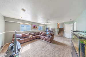 Living area with carpet floors, a textured ceiling, and a ceiling fan