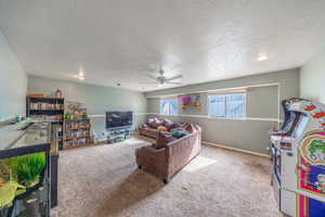 Living room featuring a ceiling fan, light colored carpet, and a textured ceiling
