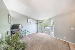 Spare room featuring lofted ceiling and light carpet