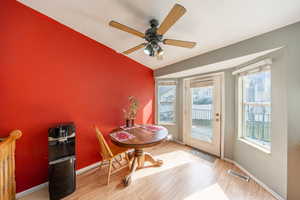 Dining space with vaulted ceiling, a ceiling fan, and light wood-type flooring