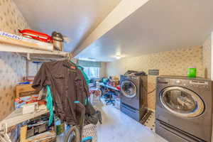Laundry area with wallpapered walls, a textured ceiling, carpet floors, and independent washer and dryer