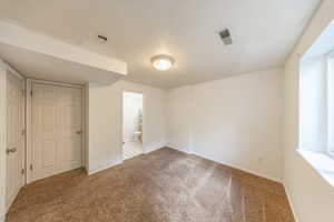 Unfurnished room featuring carpet and a textured ceiling