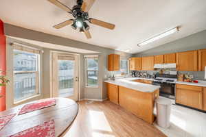 Kitchen with vaulted ceiling, light countertops, range with gas stovetop, a peninsula, and ceiling fan