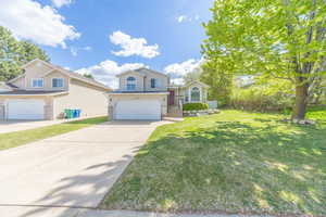Split level home with driveway, an attached garage, a front yard, and brick siding