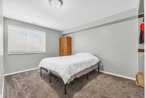 Bedroom with dark colored carpet and baseboards