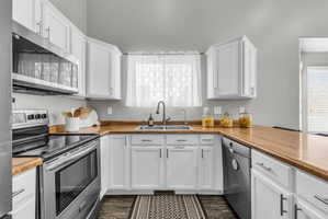 Kitchen with stainless steel appliances, white cabinets, light countertops, and dark wood finished floors