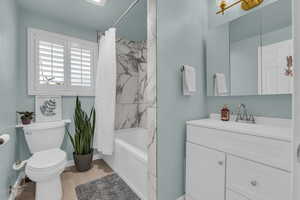 Bathroom with vanity, shower / tub combo, and light wood-type flooring