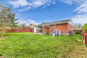 Rear view of property featuring brick siding, a fenced backyard, and a patio