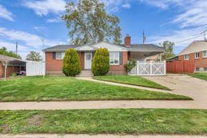 View of front of home featuring a chimney, a carport, brick siding, and driveway