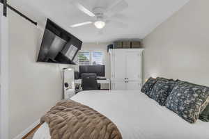 Bedroom featuring an office area, ceiling fan, a closet, light wood-style floors, and a barn door
