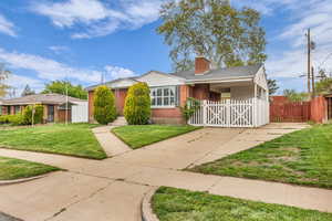 View of front facade featuring brick siding, a chimney, concrete driveway, a gate, and a shingled roof