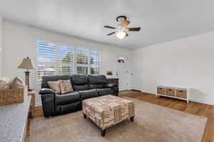 Living room with crown molding, wood finished floors, and a ceiling fan