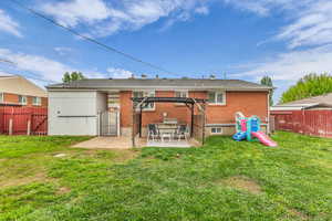 Back of property with a gate, a fenced backyard, a patio area, and brick siding