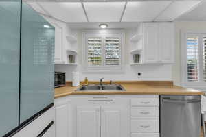 Kitchen featuring open shelves, stainless steel appliances, and white cabinetry