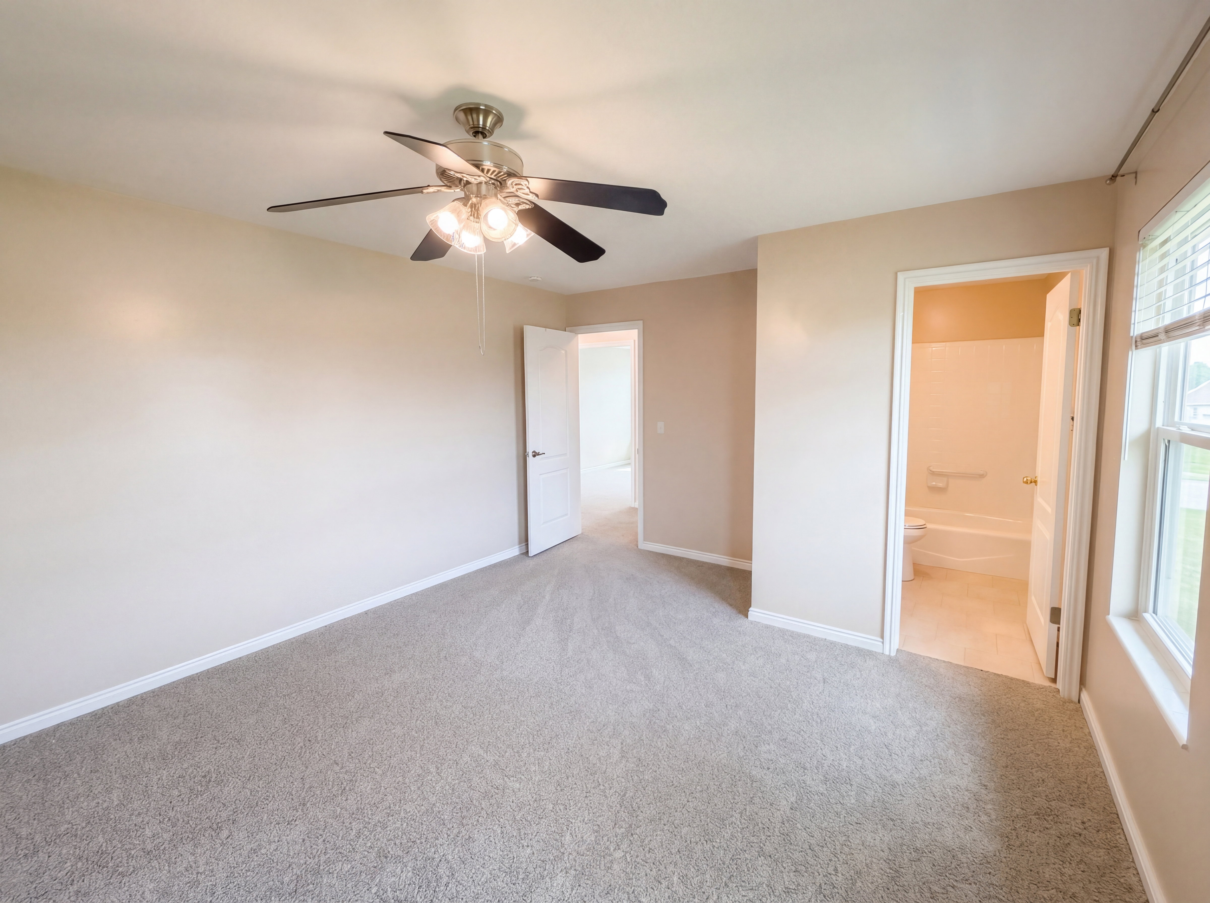Unfurnished bedroom featuring light colored carpet, ceiling fan, and ensuite bathroom