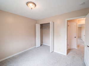 Unfurnished bedroom featuring light carpet and a closet