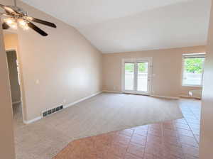 Unfurnished room featuring light colored carpet, light tile patterned flooring, a ceiling fan, and lofted ceiling