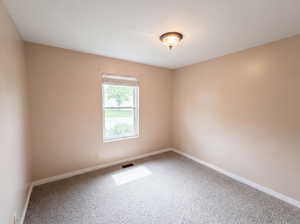 Empty room with light colored carpet and baseboards