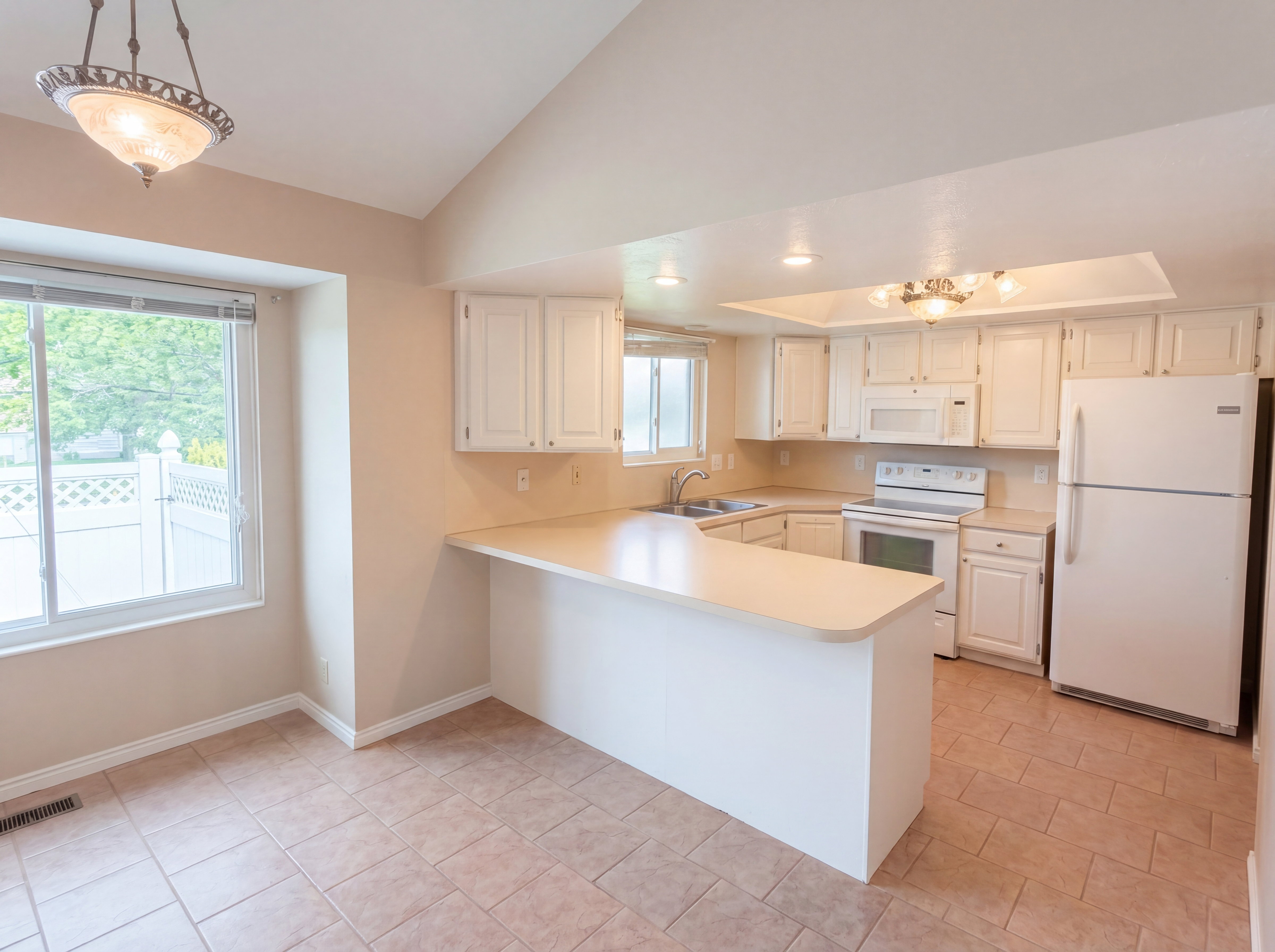 Kitchen featuring light countertops, white appliances, white cabinetry, a peninsula, and vaulted ceiling