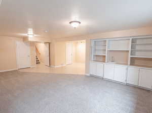 Unfurnished living room featuring light carpet and baseboards
