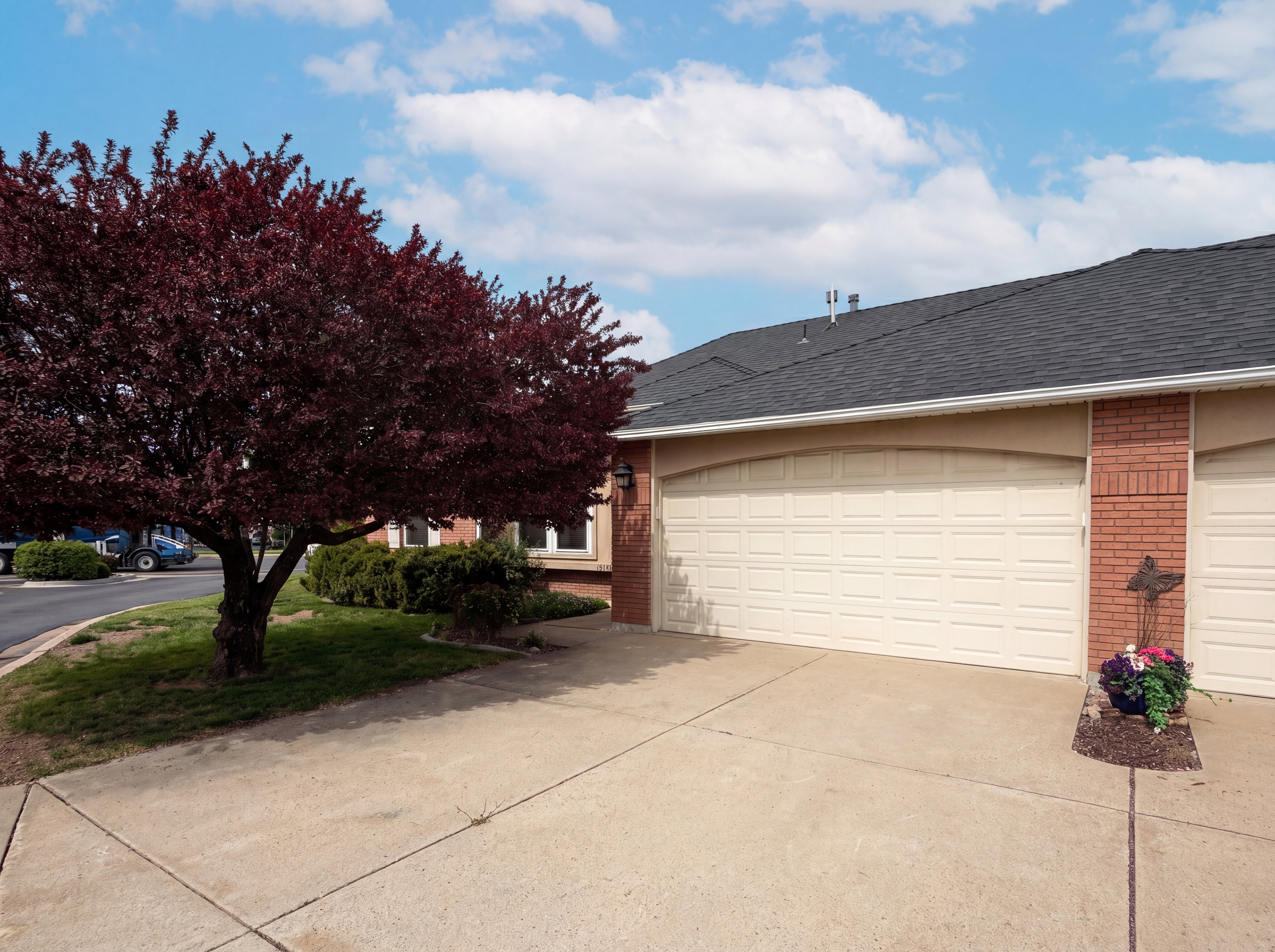 View of side of property with a shingled roof, brick siding, driveway, and an attached garage