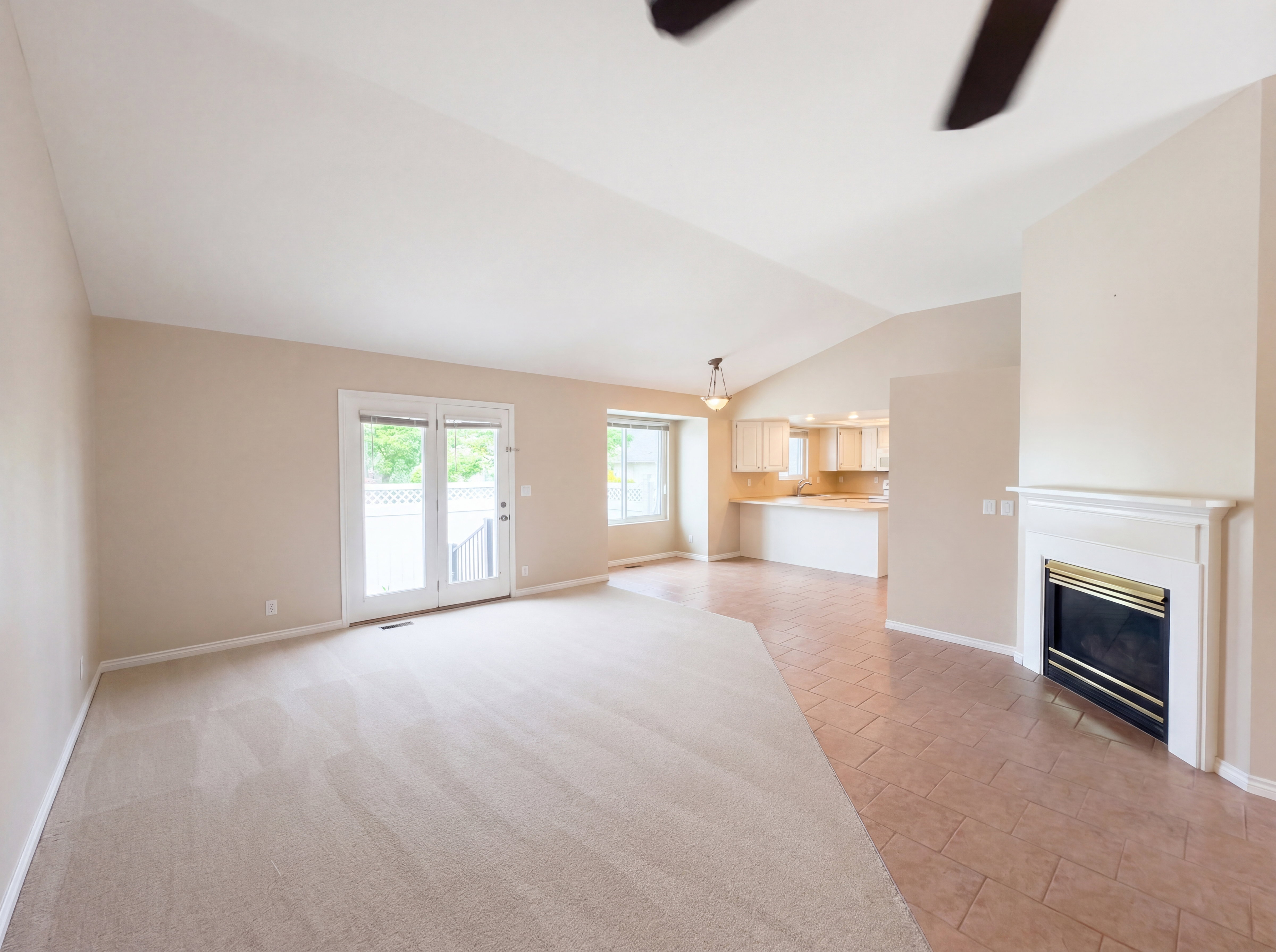 Unfurnished living room featuring ceiling fan, vaulted ceiling, a glass covered fireplace, and light tile patterned flooring