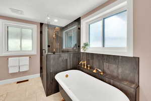 Bathroom with a shower stall, a soaking tub, and light tile patterned flooring