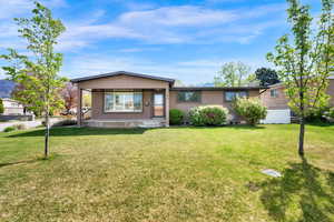 View of front of home with covered porch, a front yard, and stucco siding