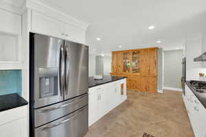 Kitchen featuring stainless steel appliances, two tone cabinetry, recessed lighting, dark stone counters, and open shelves