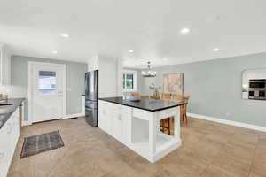 Kitchen with a kitchen island, stainless steel appliances, white cabinets, and hanging lights