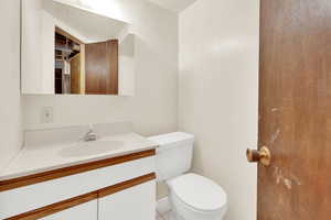 1/2 bathroom in basement featuring vanity and toilet