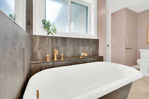 Full bathroom featuring a freestanding bath and light tile patterned flooring
