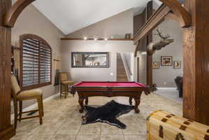 Rec room featuring arched walkways, vaulted ceiling, light tile patterned floors, and billiards