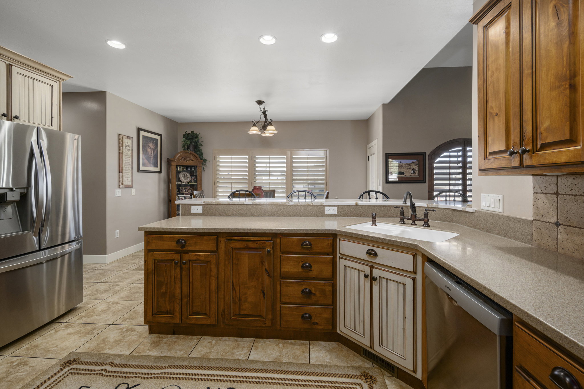 Kitchen with stainless steel appliances, a peninsula, a chandelier, and light stone countertops