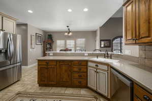 Kitchen with stainless steel appliances, a peninsula, a chandelier, and light stone countertops