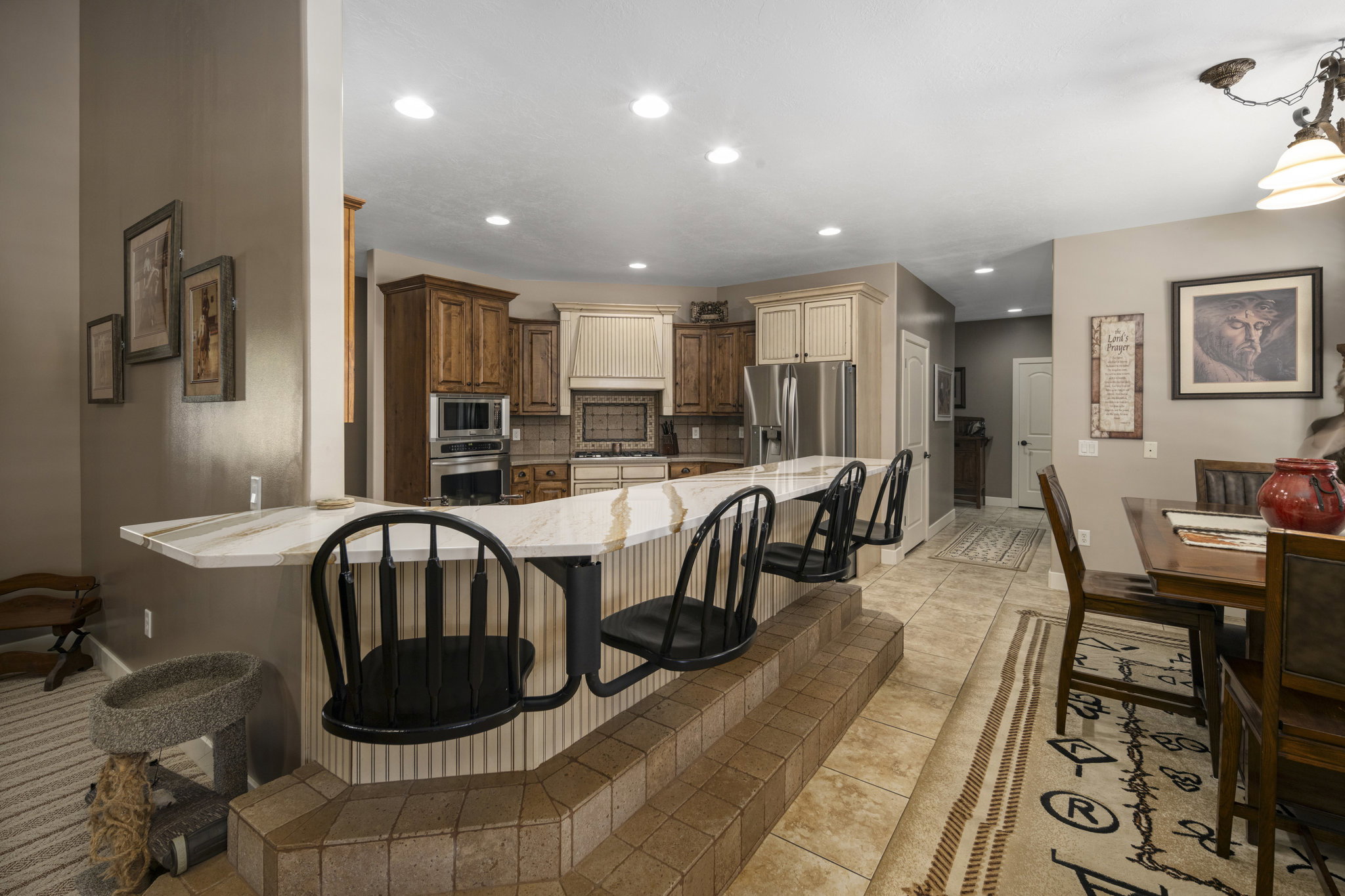 Kitchen featuring a kitchen breakfast bar, stainless steel appliances, light stone counters, recessed lighting, and tasteful backsplash