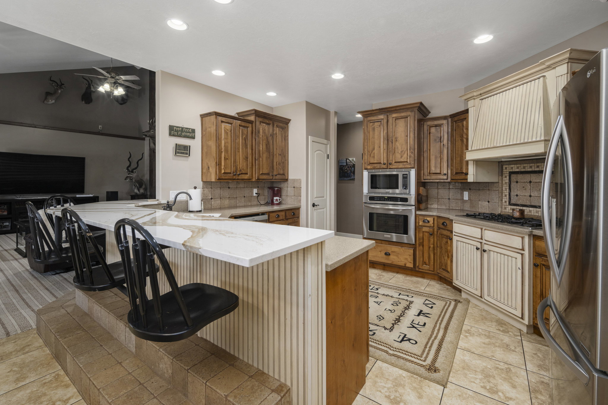 Kitchen featuring a peninsula, a breakfast bar area, stainless steel appliances, wood finish cabinets, and light stone countertops