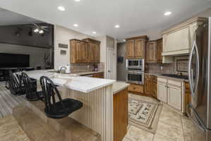 Kitchen featuring a peninsula, a breakfast bar area, stainless steel appliances, wood finish cabinets, and light stone countertops