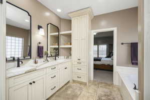 Bathroom featuring ensuite bathroom, double vanity, a garden tub, plenty of natural light, and recessed lighting