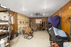 Garage with a ceiling fan and wood walls