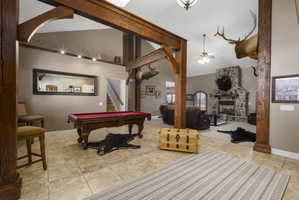 Playroom with a stone fireplace, lofted ceiling, light tile patterned floors, ceiling fan, and billiards