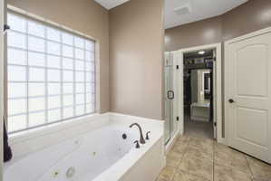 Bathroom featuring a shower stall, a whirlpool tub, and light tile patterned flooring