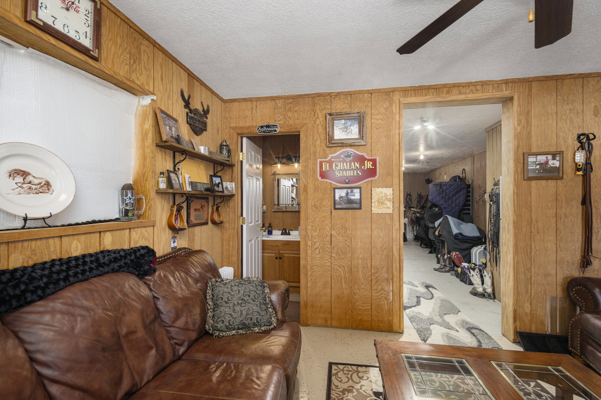 Living room featuring a textured ceiling, wooden walls, and a ceiling fan