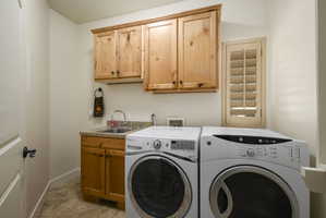 Laundry room featuring cabinet space, washer and dryer, and light tile patterned flooring
