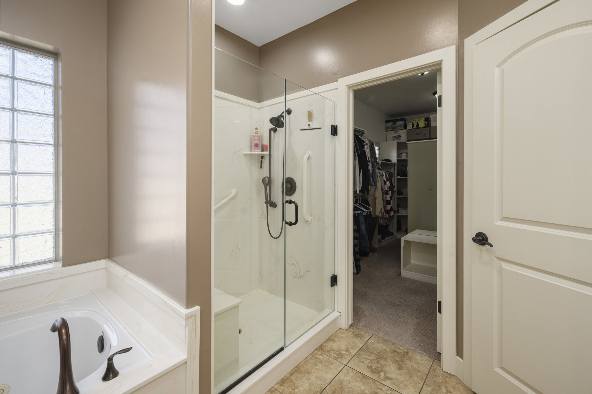 Full bath featuring a walk in closet, a bath, a shower stall, light colored carpet, and light tile patterned floors