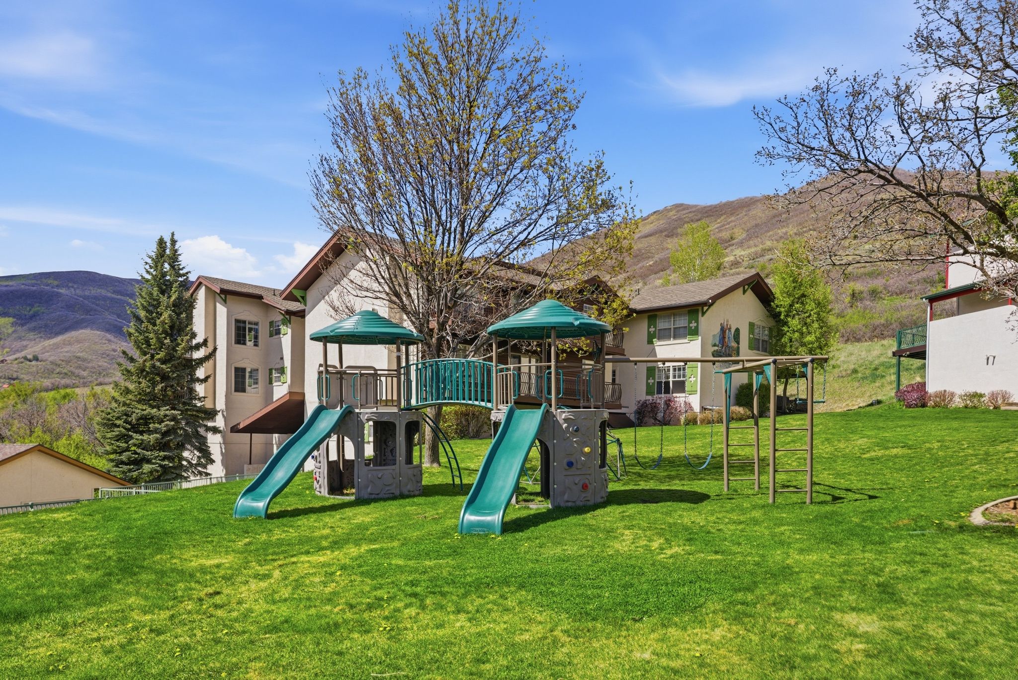 Community playground with a mountain view and a lawn