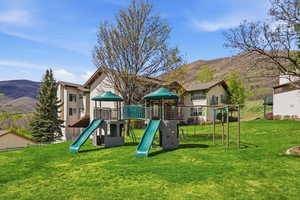 Community playground with a mountain view and a lawn