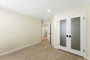 Bedroom featuring light wood-style flooring, french doors, a closet, and recessed lighting. Flexible layout allows for different furniture arrangements to suit your needs.