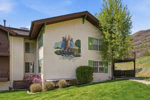 View of side of Swiss Oaks condo with stucco siding and a lawn