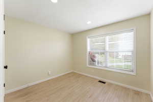 Well-sized bedroom with practical storage and a simple, calming layout. Featuring light wood-type flooring and recessed lighting.